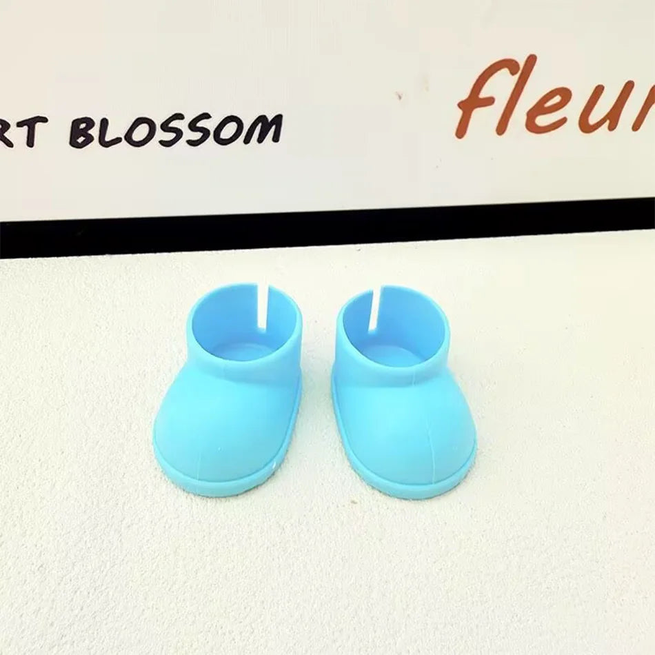 A pair of plain light blue miniature chunky boots for a Labubu figure, with a smooth texture and thick soles, sitting on a white surface.