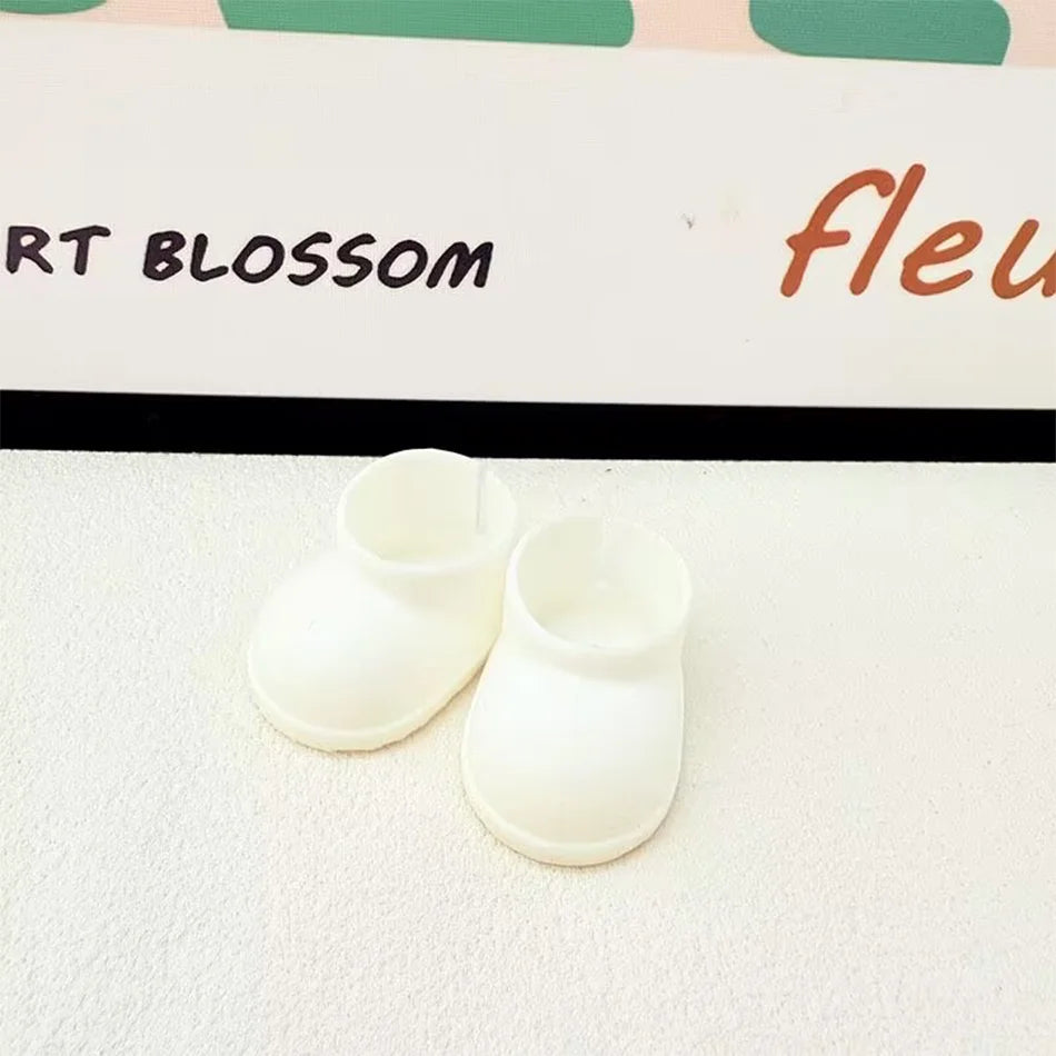 A pair of plain white miniature chunky boots for a Labubu figure, with a smooth texture and thick soles, sitting on a white surface.