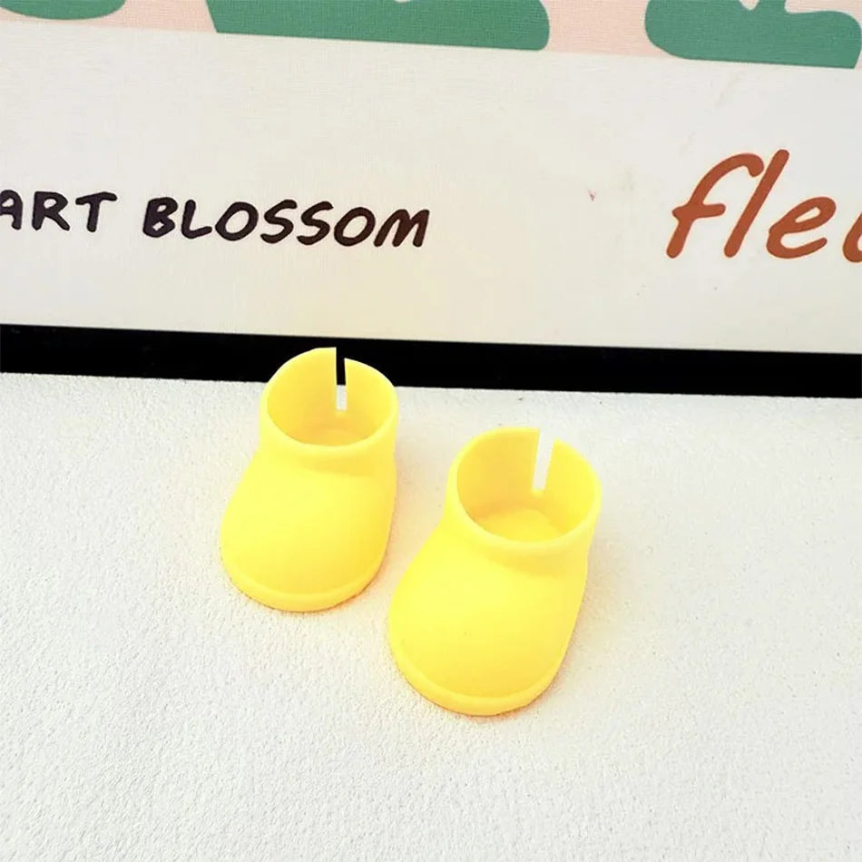 A pair of plain yellow miniature chunky boots for a Labubu figure, with a smooth texture and thick soles, sitting on a white surface.