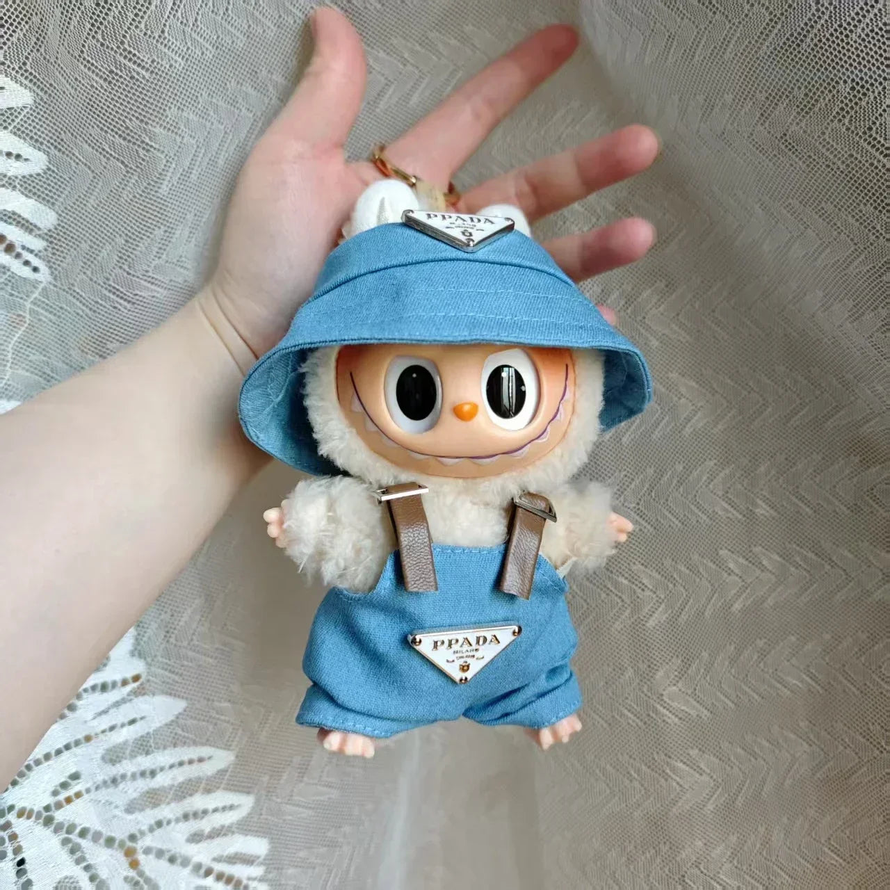 Labubu wearing a denim 'PPADA' fashion outfit with an overall, a shirt, and a bucket hat.