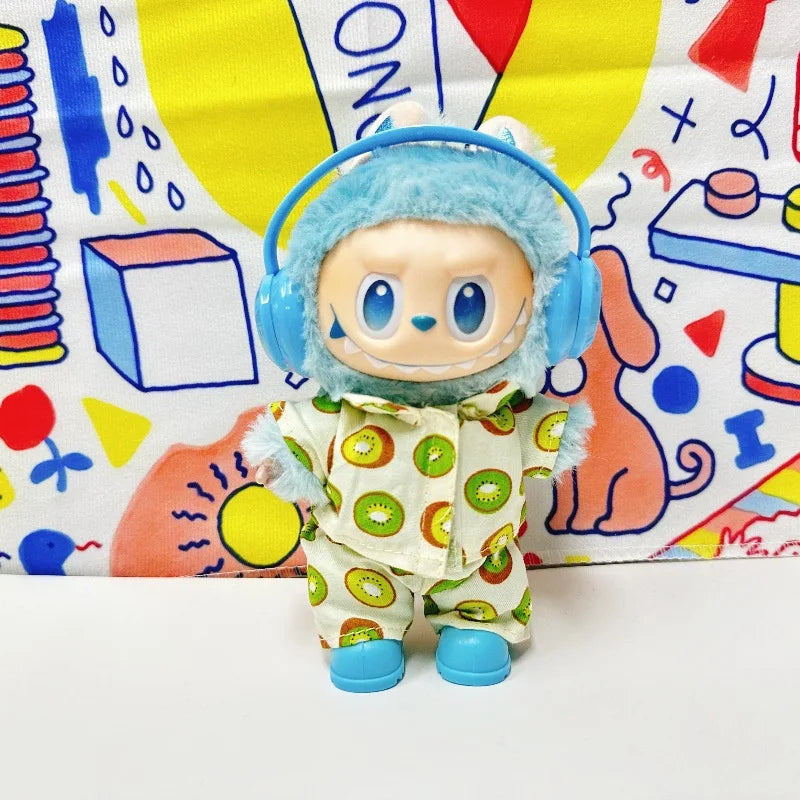 A Labubu figure wearing a light-colored two-piece pajama set with a green kiwi fruit print. The figure is also wearing blue headphones and blue shoes.