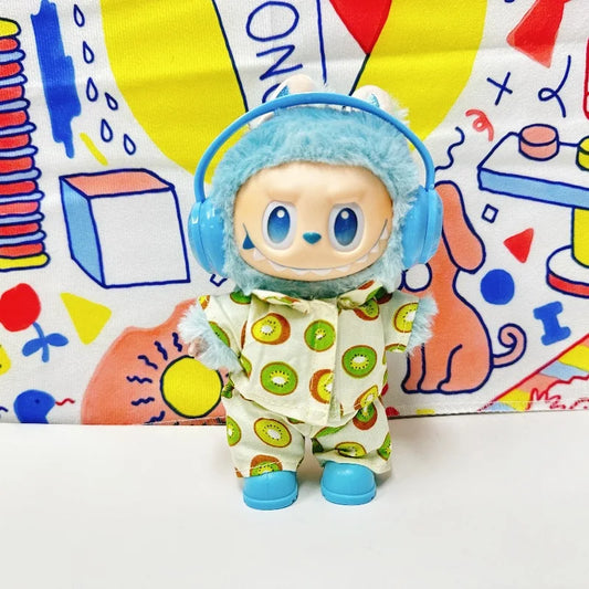 A Labubu figure wearing a light-colored two-piece pajama set with a green kiwi fruit print. The figure is also wearing blue headphones and blue shoes.