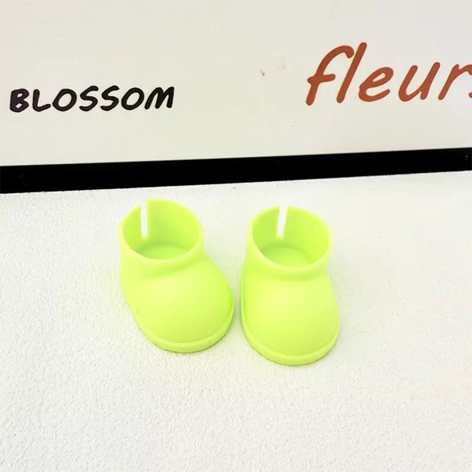 A pair of plain neon yellow miniature chunky boots for a Labubu figure, with a smooth texture and thick soles, sitting on a white surface.

