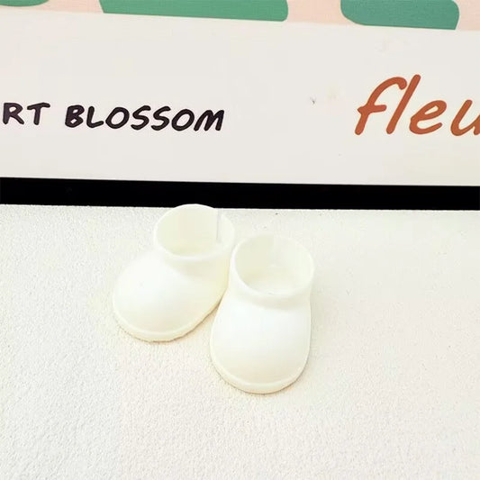 A pair of plain white miniature chunky boots for a Labubu figure, with a smooth texture and thick soles, sitting on a white surface.

