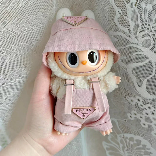 Labubu wearing a pink 'PPADA' fashion outfit with an overall, a shirt, and a bucket hat.
