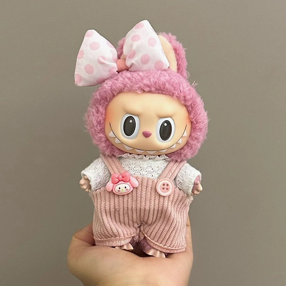 Labubu wearing a pink bunny outfit with corduroy overalls, a lace top, and a fluffy hoodie with a large polka-dot bow.
