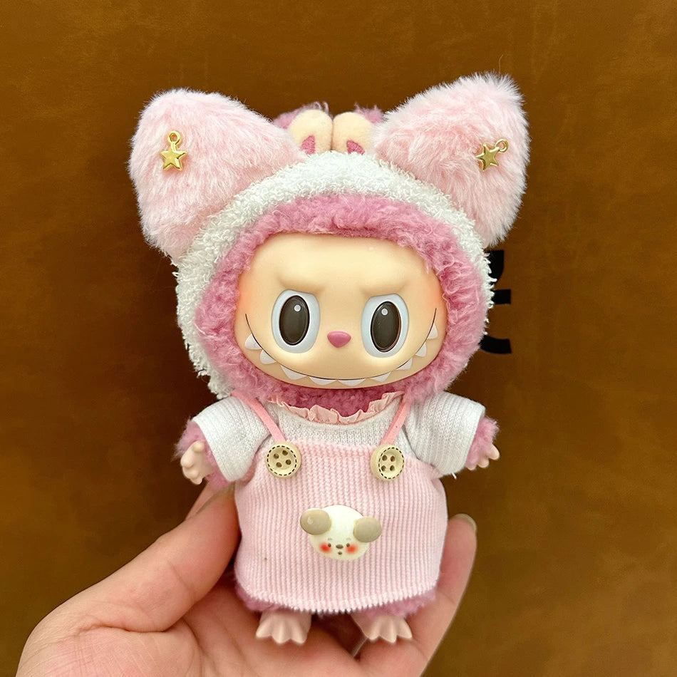 Labubu wearing a strawberry sheep outfit with a pink overall, ruffled shirt, and a two-toned plush hoodie with ears.