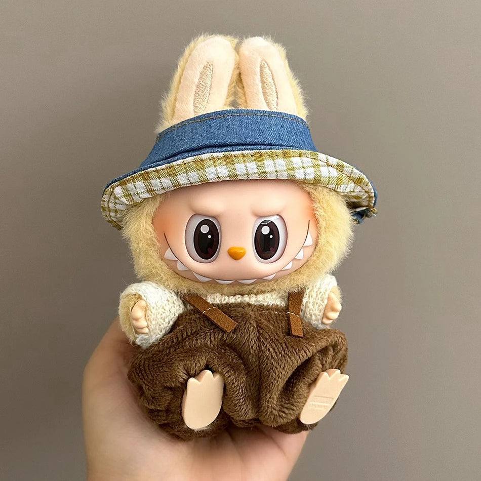 Labubu wearing a rustic farmer outfit with brown corduroy overalls, a cream sweater, and a plaid bucket hat.
